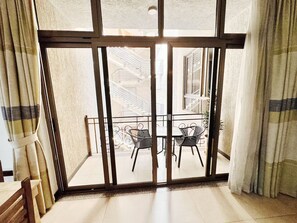 A room with a sliding glass door leading to an outdoor balcony with two chairs and a table. - Rankset Guesthouse apartment (Addis Ababa)