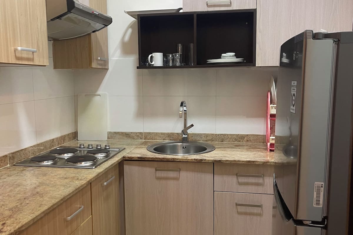 A compact kitchen with a gas stove, sink, and a refrigerator.
