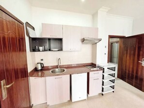 A compact kitchen with a sink, cabinets, and a stove. - Rankset Guesthouse apartment (Addis Ababa)