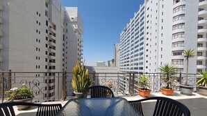 Terraza en la azotea con mesa de billar, plantas en macetas y vistas de edificios altos aledaños.
