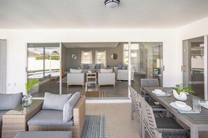 A modern living room with a sofa, coffee table, and dining area with a table and chairs. - VRCC Villa White Palm (Cape Coral)