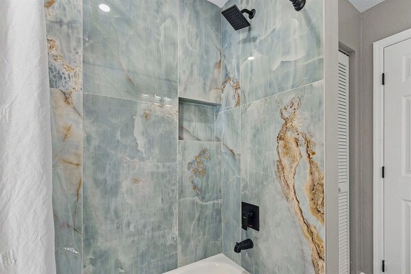 A bathroom with a large mirror, a shower, and a toilet.