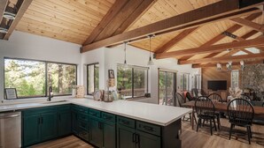 A modern kitchen with wooden beams, large windows, and a stone fireplace. - Lay-Z-Bones ~ AC & Pool Access! (Dorrington)