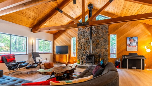 A cozy living room with a stone fireplace, wooden beams, and large windows. - Lay-Z-Bones ~ AC & Pool Access! (Dorrington)