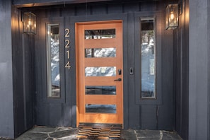 A wooden front door with glass panels and the number 2214.