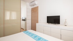 Ein Schlafzimmer mit Bett, Fernseher, Kleiderschrank und Schreibtisch.