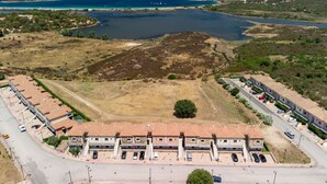 Ein Küstengebäude mit Parkplatz, umgeben von hügeliger Landschaft und einer Wasserfläche.