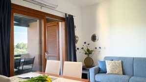 Ein Zimmer mit Esstisch, Stühlen, einer Couch und Blick ins Freie.