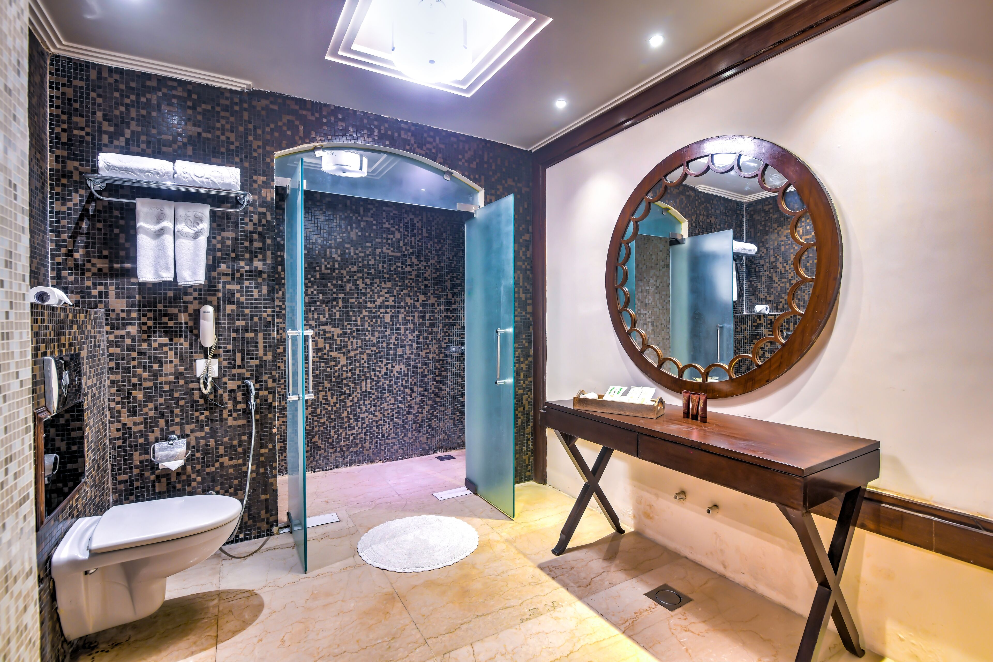 Een moderne badkamer met een douchecabine van glas, een toilet en een wastafel met spiegel.