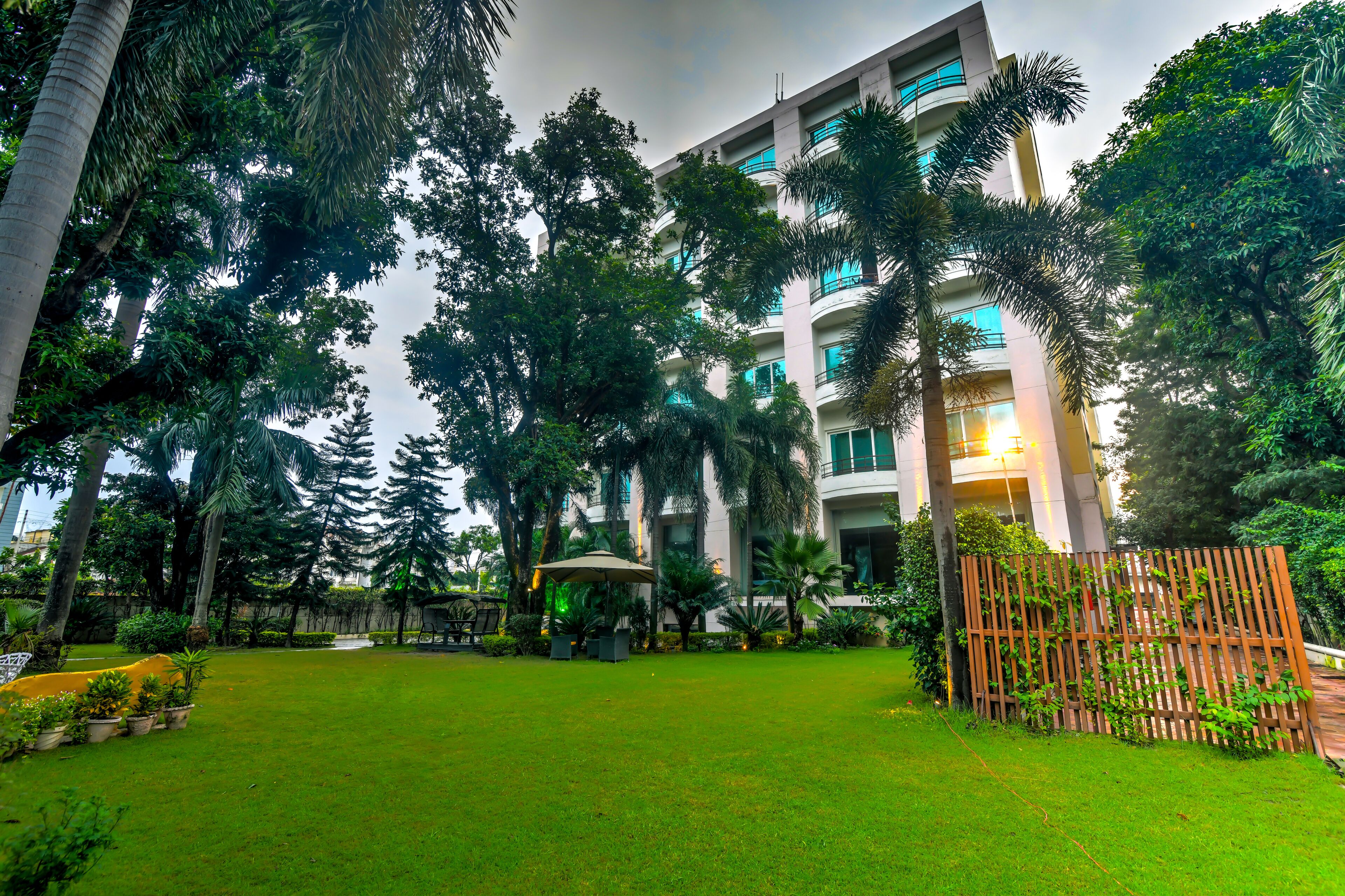 A hotel with a lush garden, a gazebo, and a modern building with balconies.