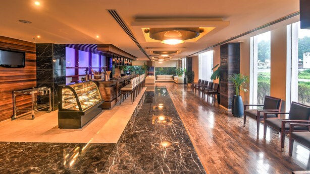 Een hotellobby met een marmeren vloer, een receptiebalie, een zithoek en grote ramen met uitzicht.