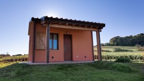 A small, single-story building with a wooden roof and a door, surrounded by a grassy field and trees. - Agriturismo San Giuseppe (Piombino)