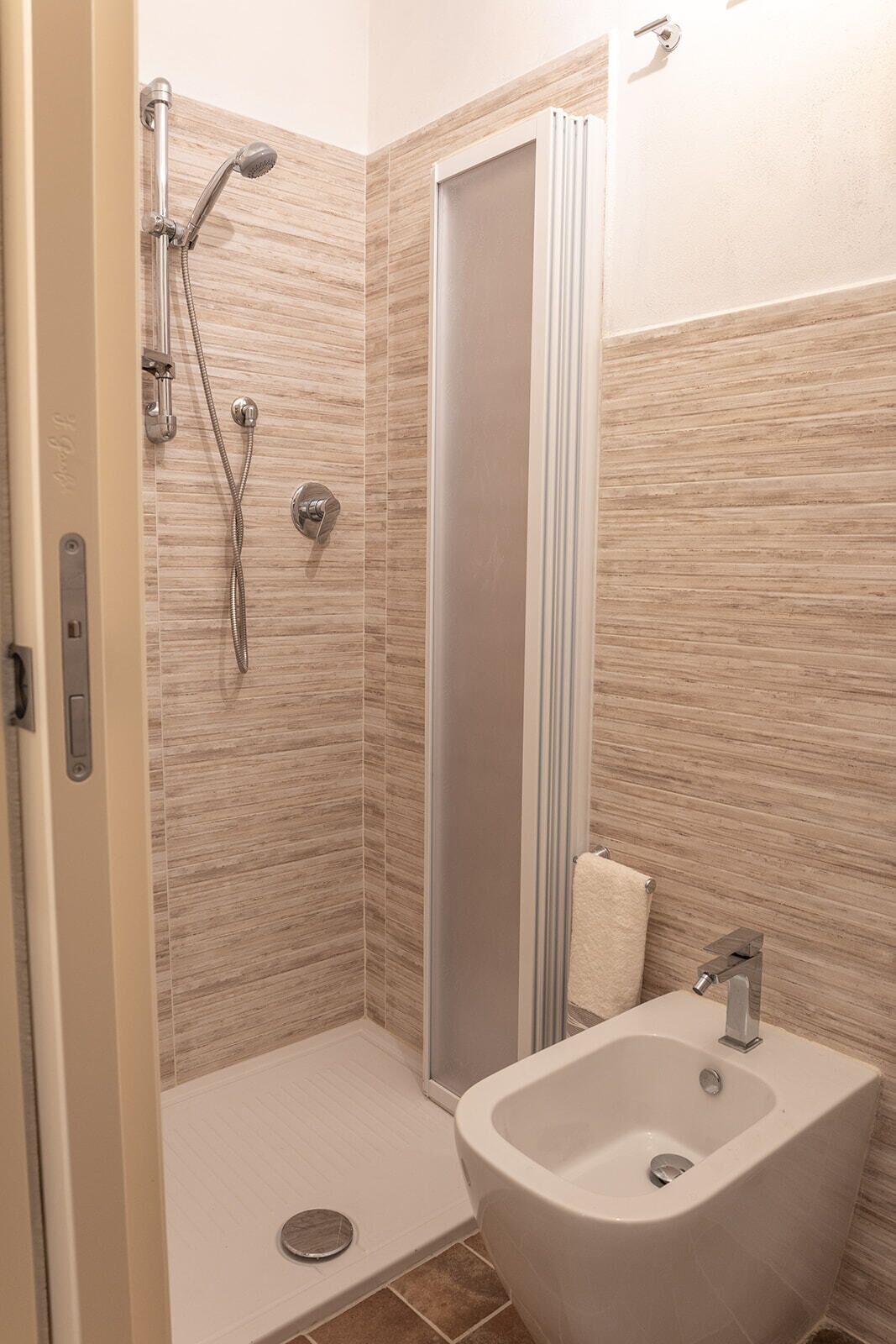 A modern bathroom with a shower, a sink, and a towel rack.