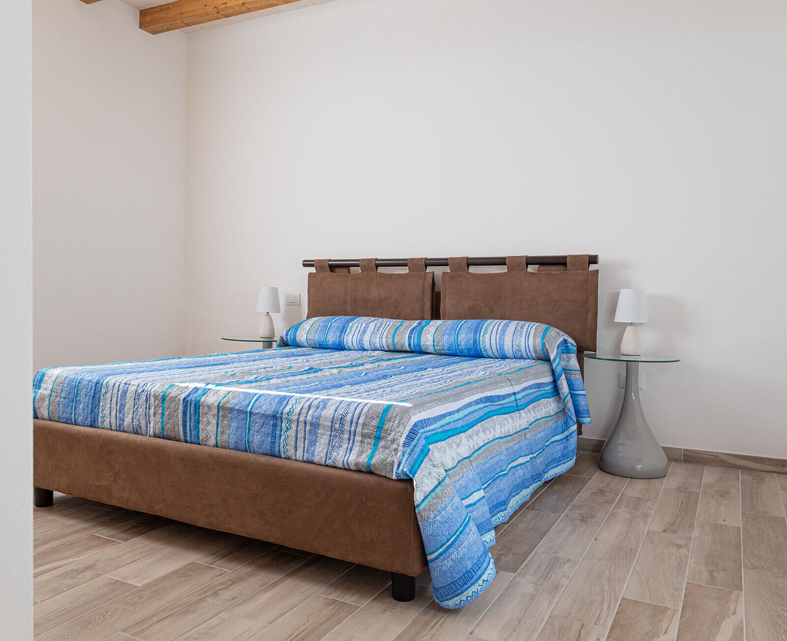 Ein Schlafzimmer mit einem Bett, zwei Nachttischen und einer Lampe auf jeder Seite.