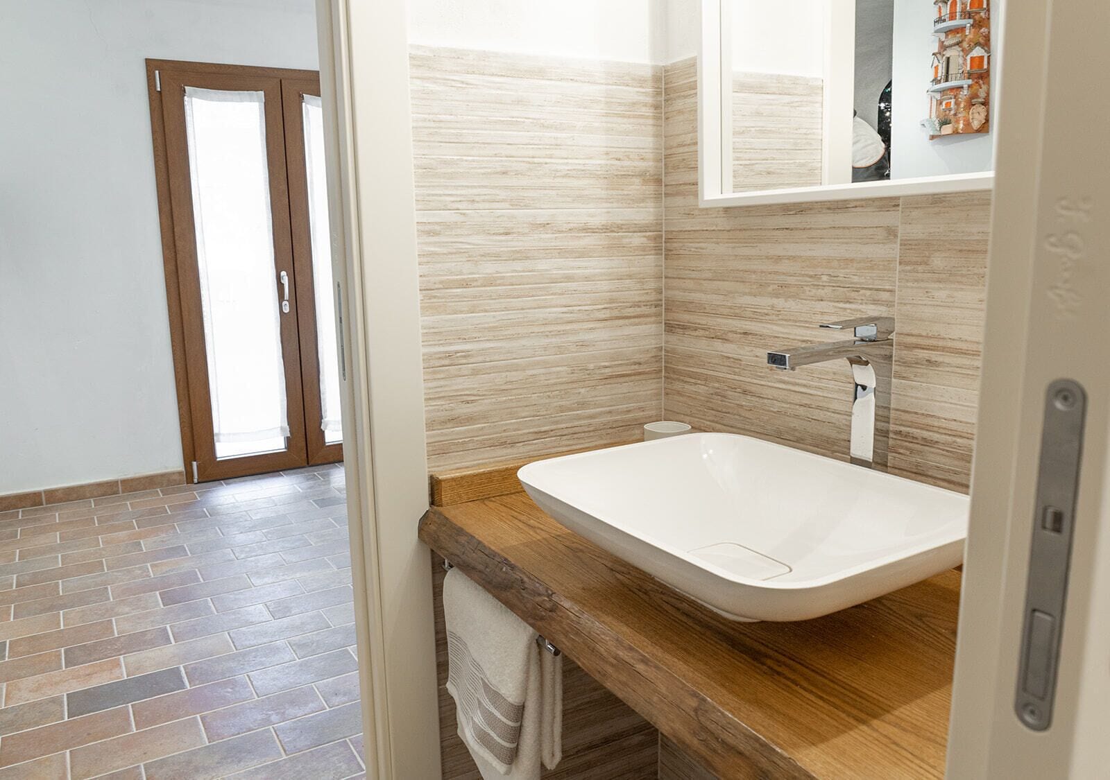 A bathroom with a wooden vanity, a white sink, and a mirror.