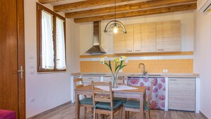 A compact kitchen with wooden cabinets, a built-in oven, and a hanging light fixture. - Agriturismo San Giuseppe (Piombino)