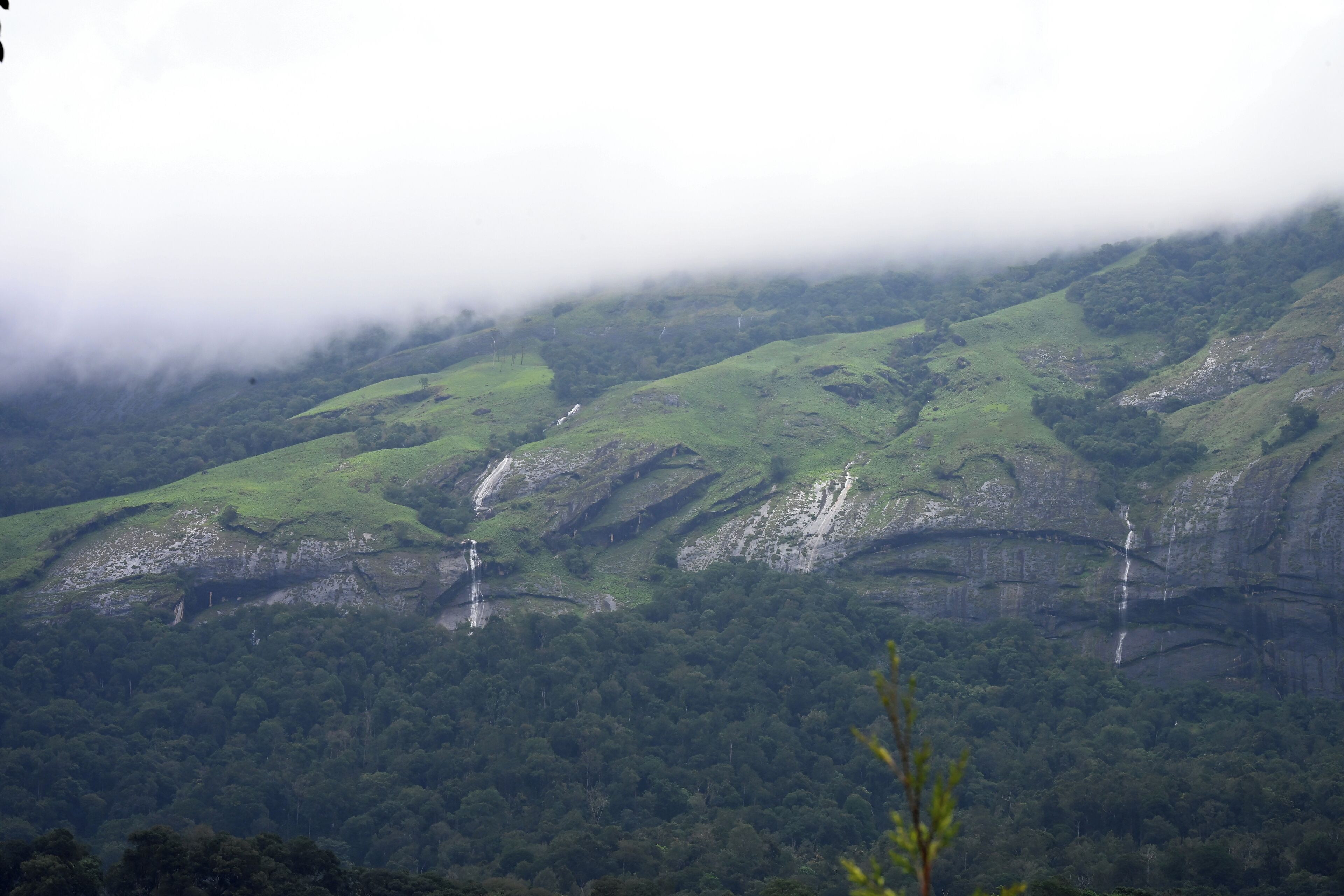 A mountainous landscape with waterfalls and dense forest.