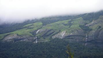A mountainous landscape with waterfalls and dense forest.