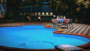 A swimming pool with a tiled deck and a table with chairs.