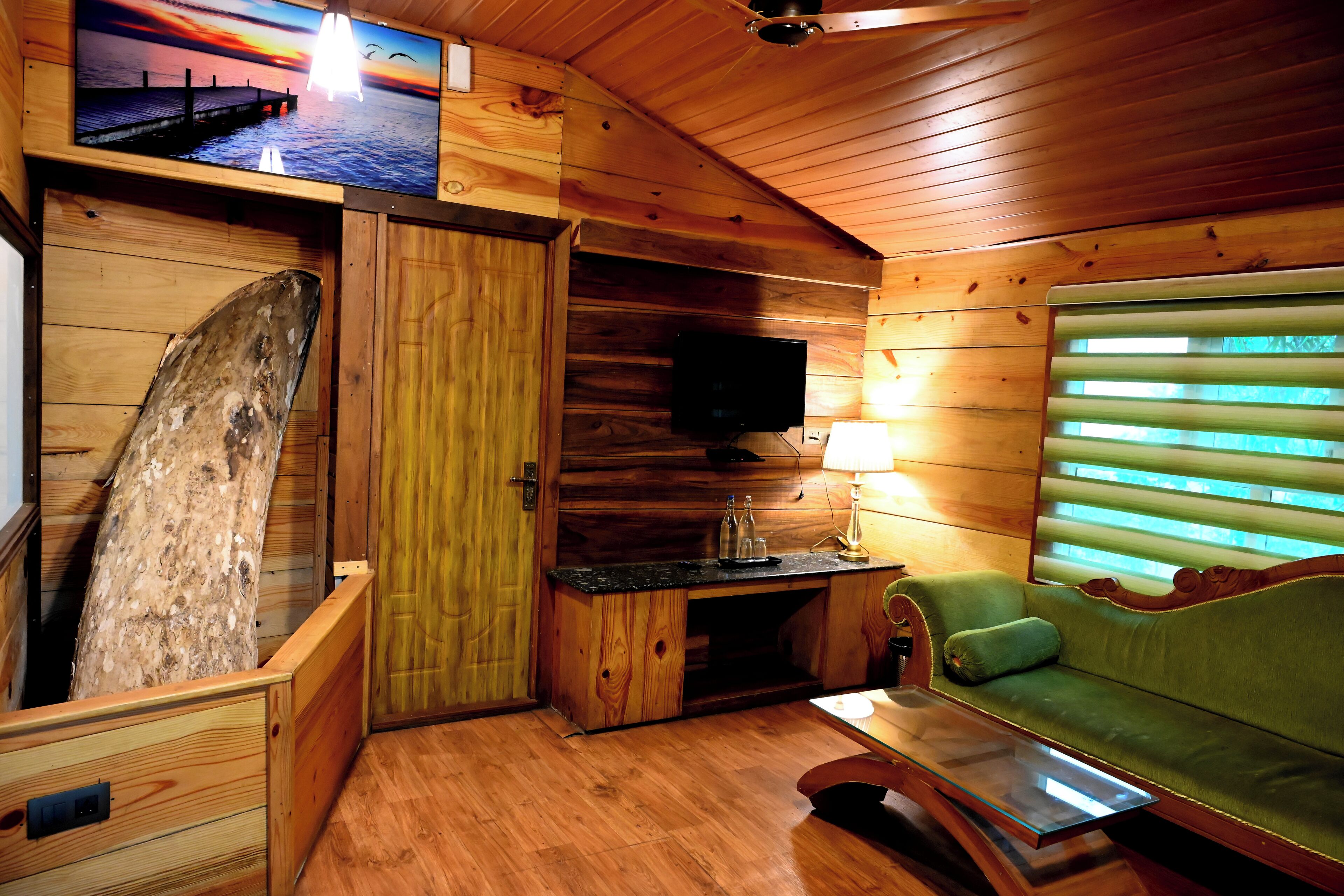 Ein gemütliches Blockhaus-Interieur mit Holzausbau, einem an der Wand montierten Fernseher, einer Couch und einem Tisch.