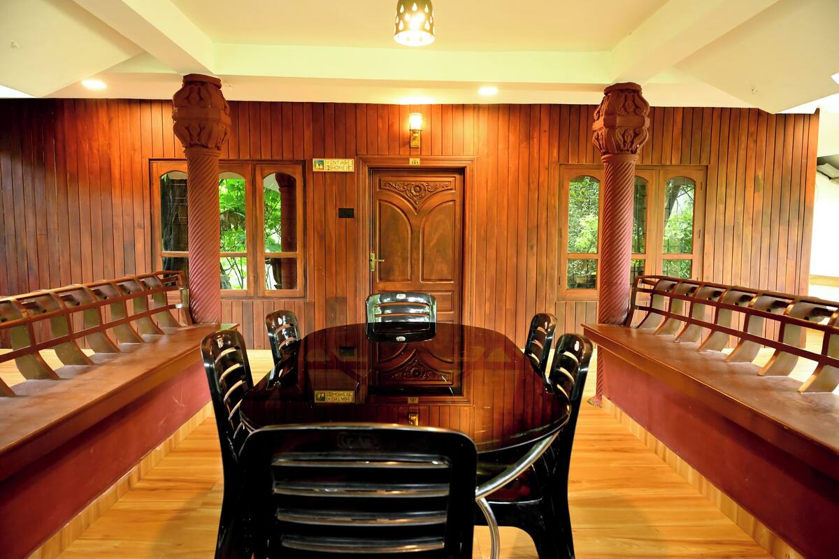 Uma sala de conferências com interior em madeira, uma grande mesa redonda e bancos ao longo das paredes.