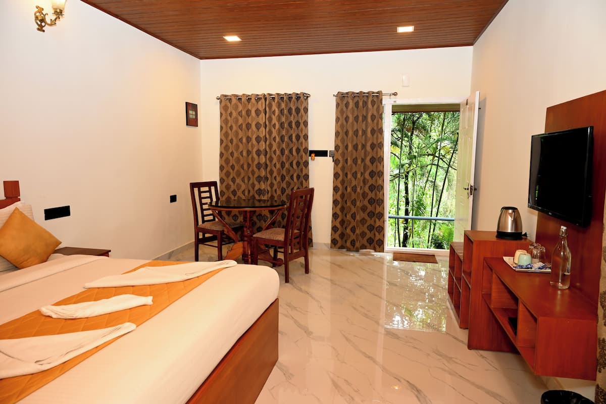 Quarto de hotel com cama, escrivaninha, televisão e varanda com cortinas.