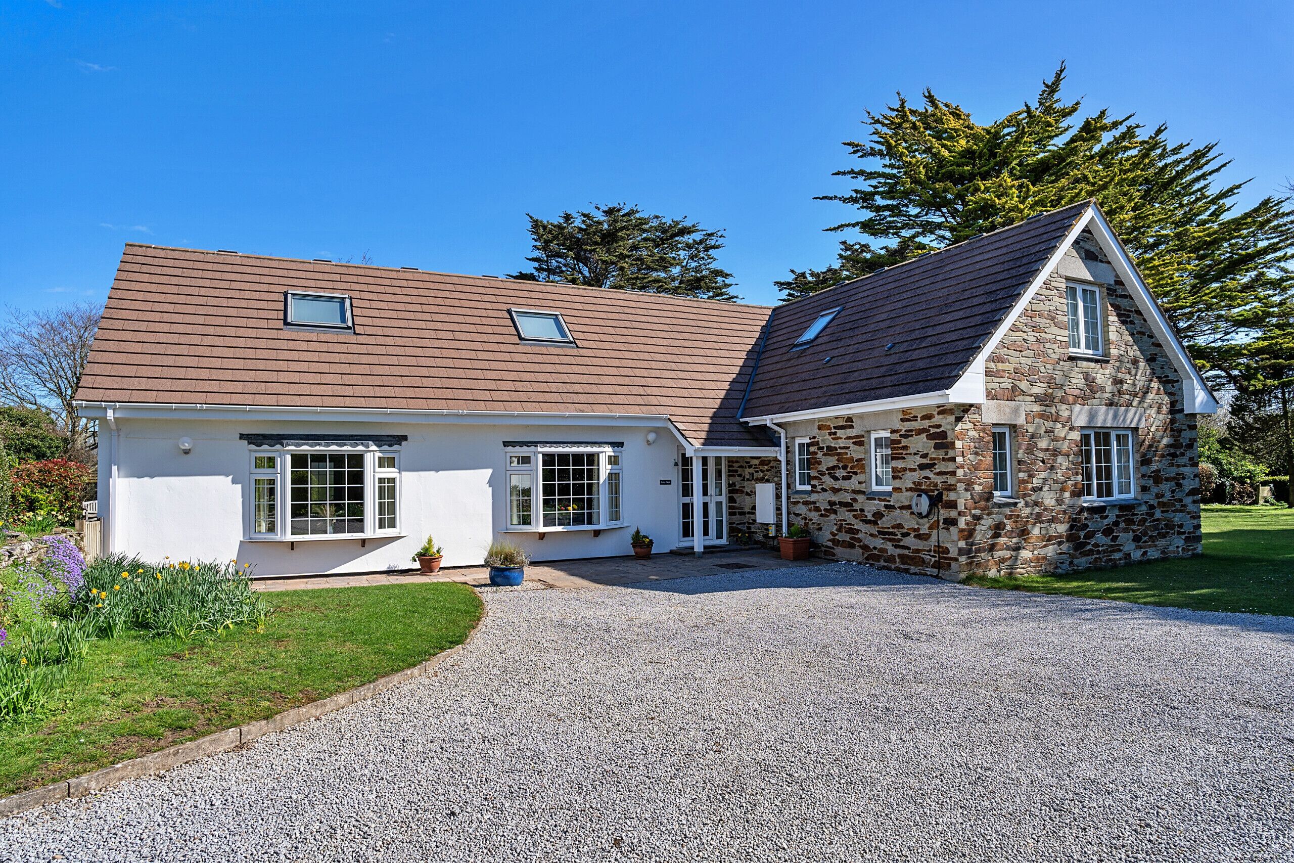 A two-story house with a gravel driveway and a stone extension.