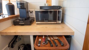 Una cocina con cafetera, microondas y utensilios sobre una encimera de madera.