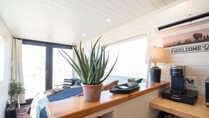 Una cocina moderna con encimera de madera, una cafetera Keurig, una planta en maceta y un cartel de bienvenida.