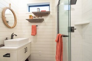 A bathroom with a white sink, mirror, and glass shower door.