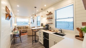 A compact kitchen with a dining area, wooden floors, and a view through the window.