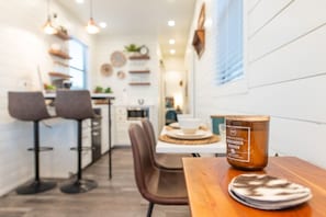 Une cuisine moderne avec un coin repas, comprenant une table en bois agrémentée d’une bougie, une chaise et un tabouret de bar.