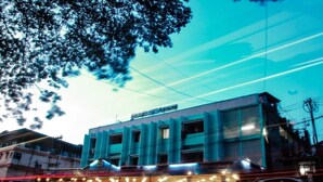 A multi-story building with a blue facade, featuring a restaurant at the ground level with outdoor seating. - Blue Sea Hotel (Port Blair)