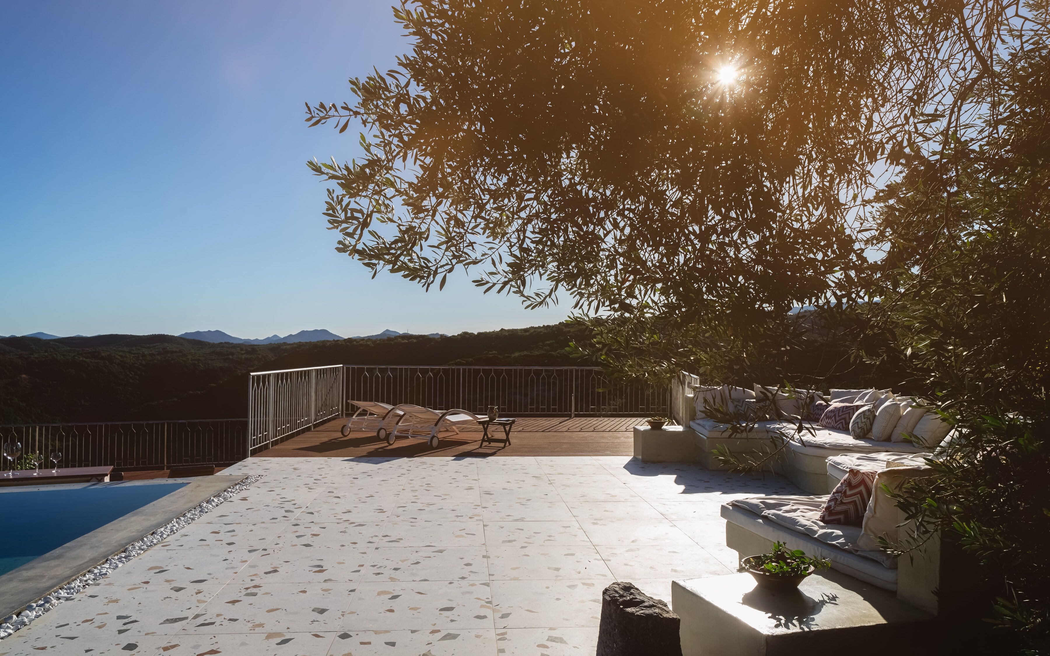A rooftop terrace with a pool, seating area, and a view of the mountains.