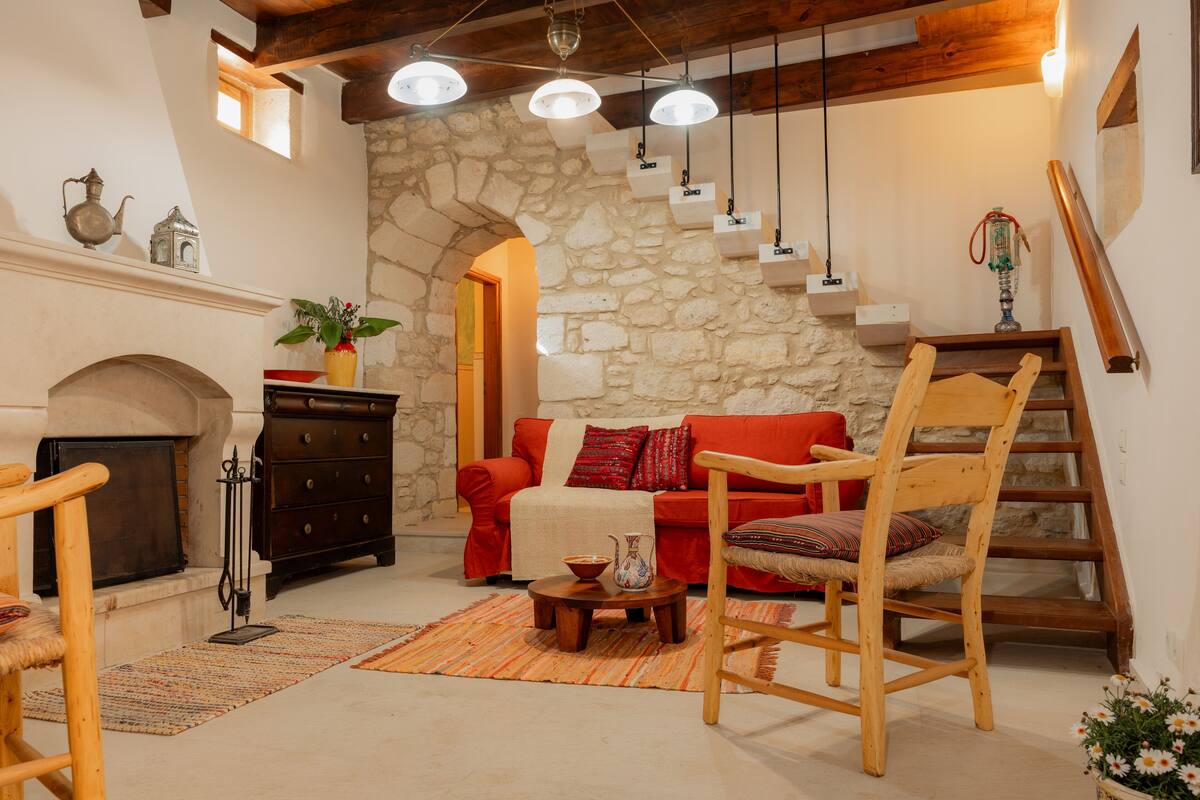 Una sala de estar acogedora con una pared de piedra, una chimenea, un sofá rojo y muebles de madera.