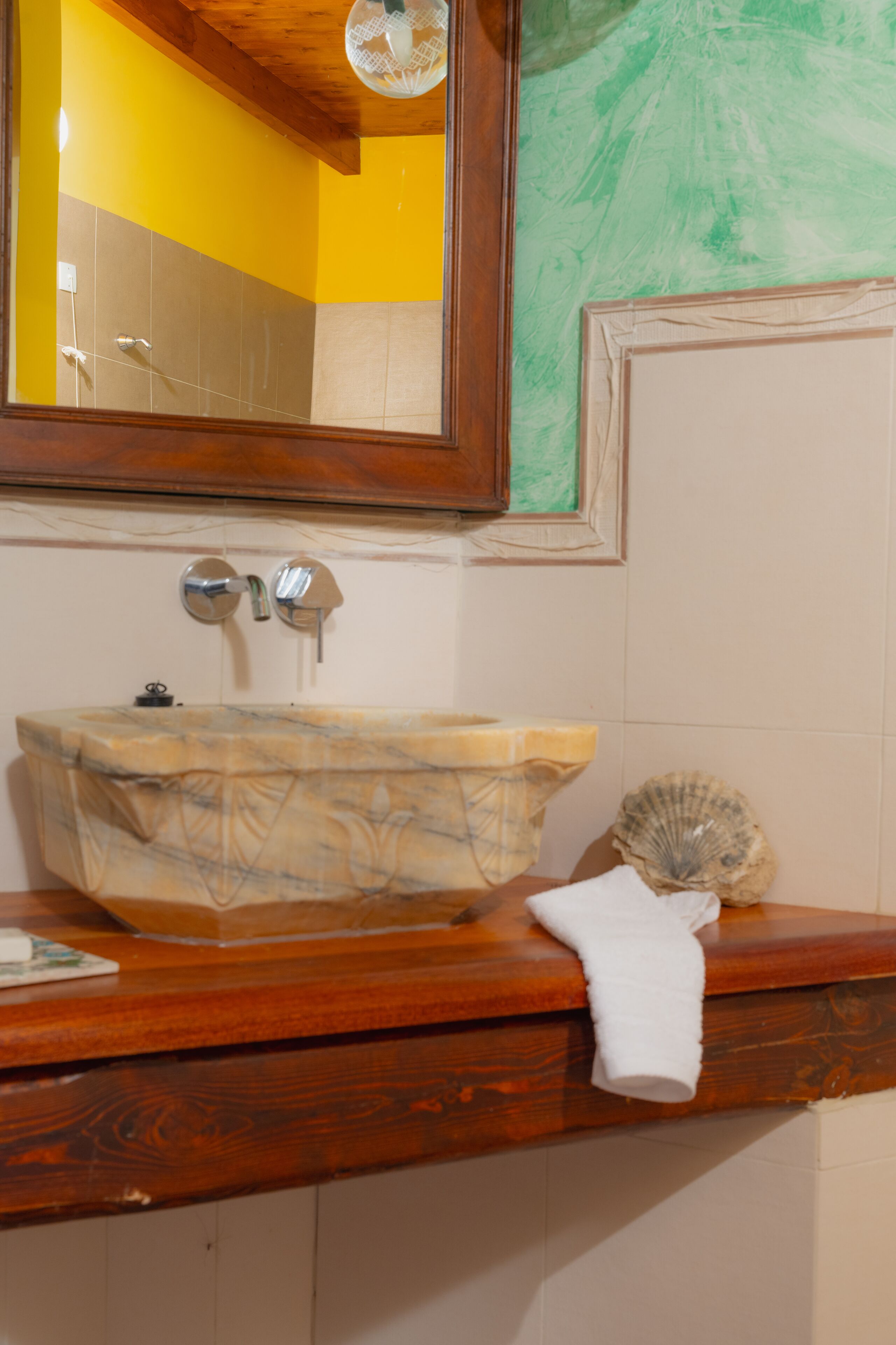 Un baño con tocador de madera, lavabo de mármol y un espejo grande.