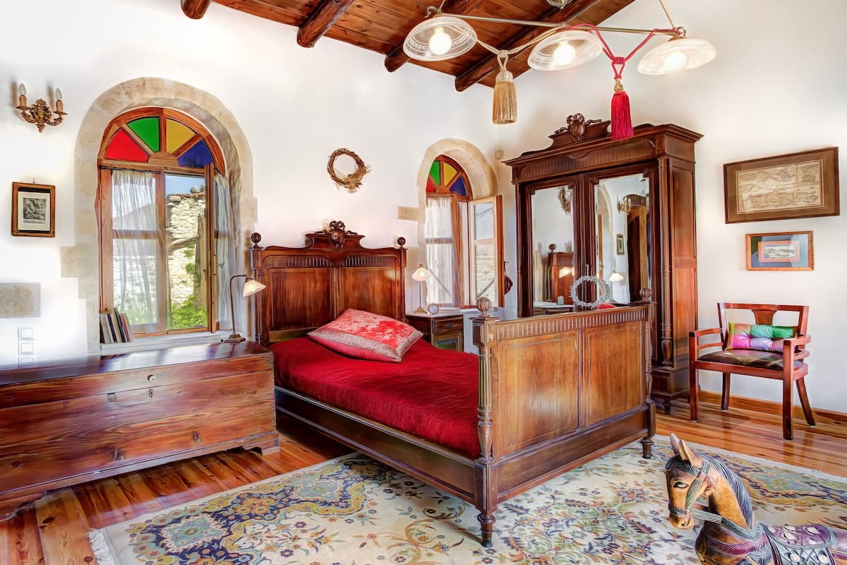 Un dormitorio tradicional con una cama de madera, un aparador, un espejo y una silla.
