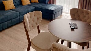 Una sala de estar moderna con un sofá azul, dos sillones y una mesa redonda de madera.