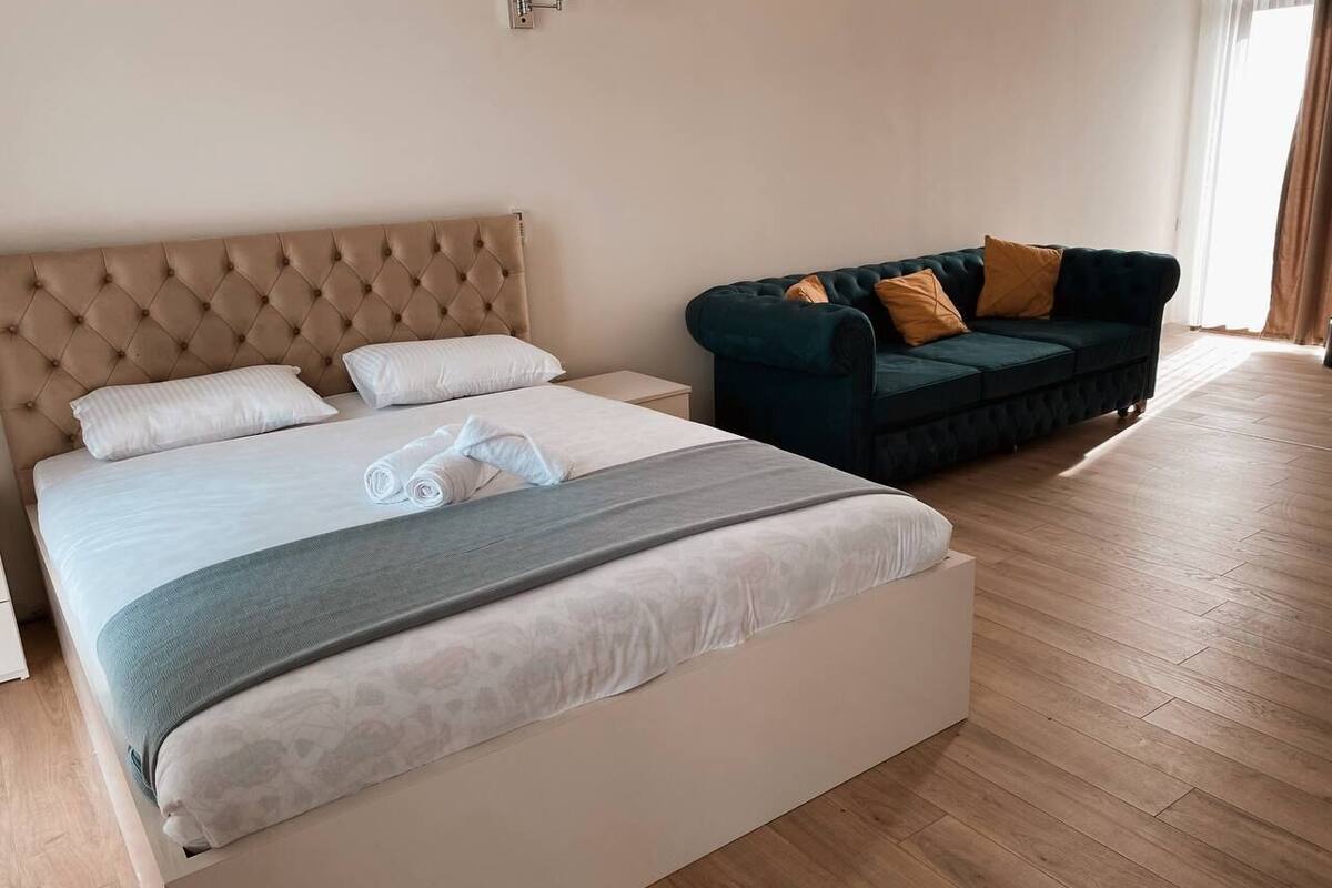 A bedroom with a bed, a sofa, and a nightstand.