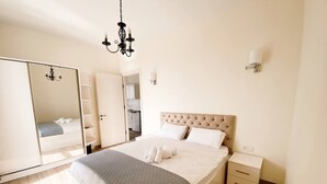 Un dormitorio con una cama grande, un armario, una mesita de noche y una araña.