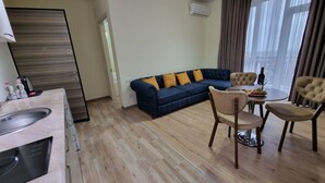 Una sala moderna con un sofá, sillas, una mesa de comedor y una zona de cocina con un fregadero y armarios.