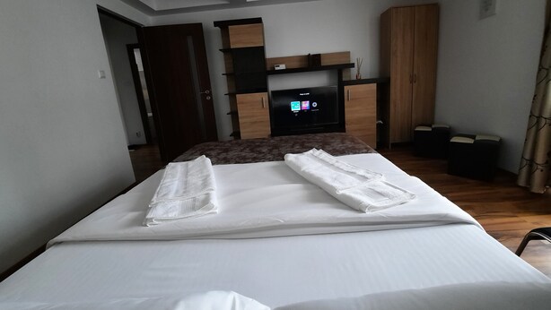 Ein Hotelzimmer mit Bett, Fernseher, Kleiderschrank und Schreibtisch.