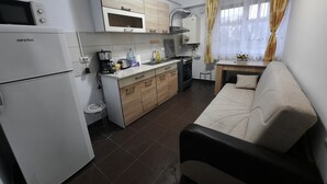 Eine kompakte Küche mit Kühlschrank, Mikrowelle, Herd und einer kleinen Essecke.