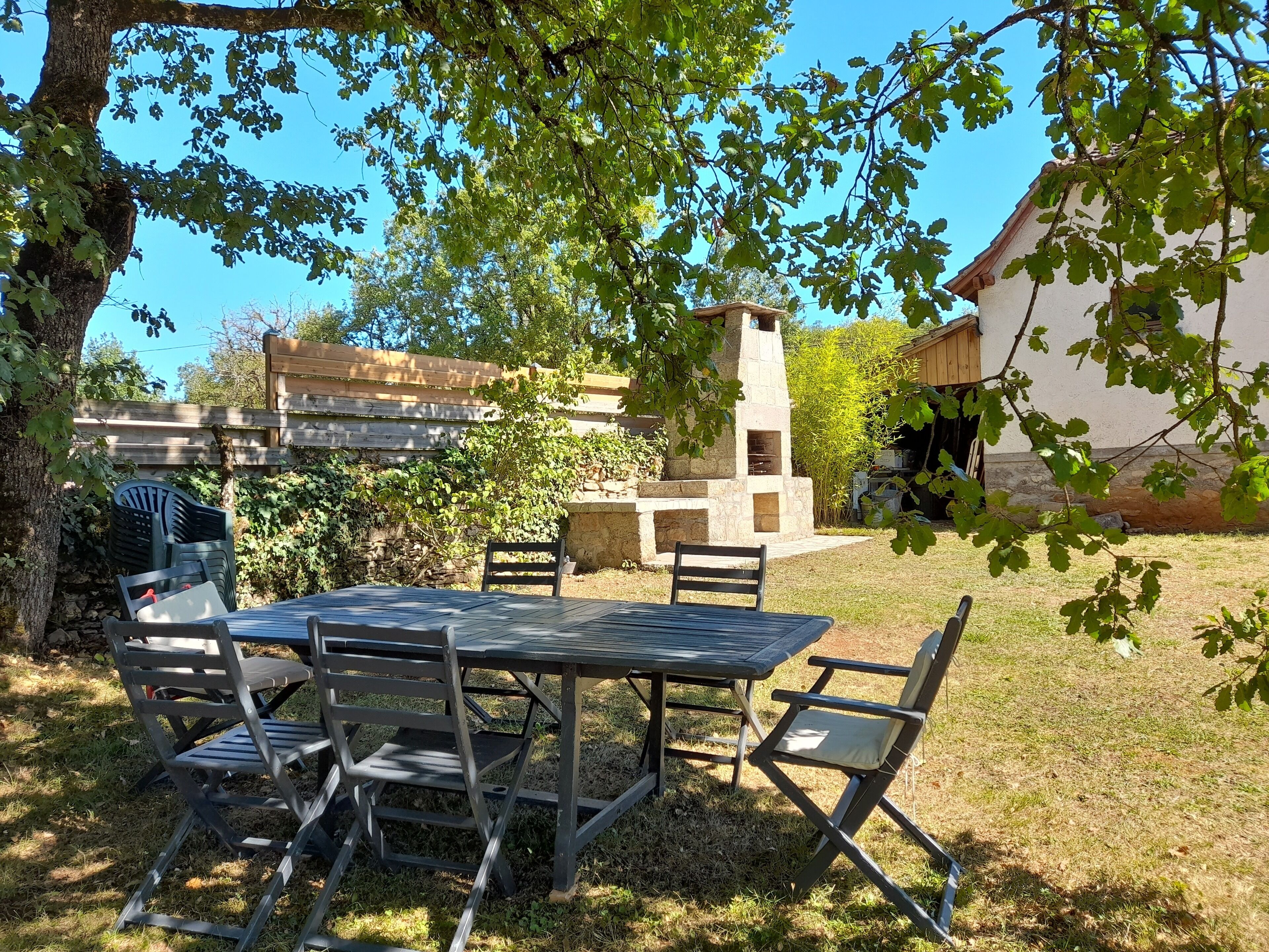 Une terrasse extérieure avec une cheminée en pierre, une table et quatre chaises.