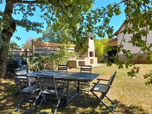 Un patio al aire libre con una chimenea de piedra, una mesa y cuatro sillas.