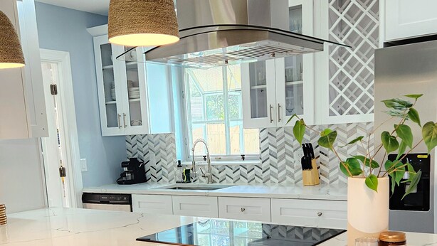 A modern kitchen with a large island, white cabinetry, and pendant lighting. - Paradise Vacation Home for entire family (Boynton Beach)