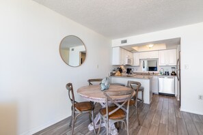 A compact kitchen with white cabinets, a central island, and a dining area with a round table and four chairs.