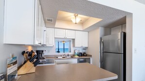 Una cocina moderna con armarios blancos, un refrigerador de acero inoxidable y una encimera con varios electrodomésticos.