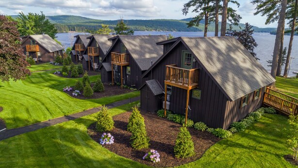 A row of cabins with balconies, a well-maintained lawn, and a lake view.