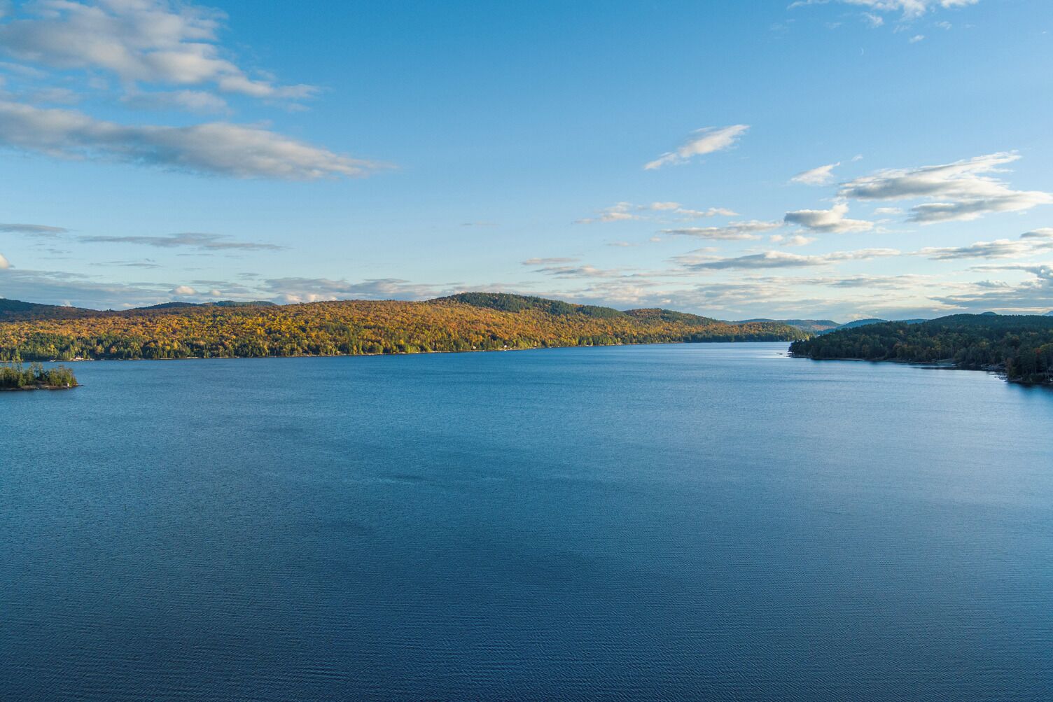 A large body of water surrounded by forested hills.